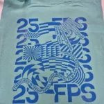 Svijetlozelena platnena vrećica s tiskanim plavim dizajnom koji prikazuje broj 25 i skraćenicu FPS. Natpis sadrži tekst Dvadeseti Internacionalni Festival Eksperimentalnog Filma i Videa te njegov prijevod na engleski: Twentieth International Experimental Film and Video Festival. Grafički elementi uključuju apstraktne linije i oblike u plavoj boji, koji stvaraju dinamičan vizualni dojam.